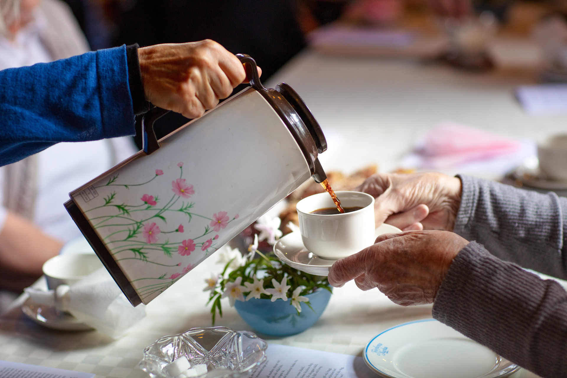 Kaffe från en blommig termos hälls upp i en kopp