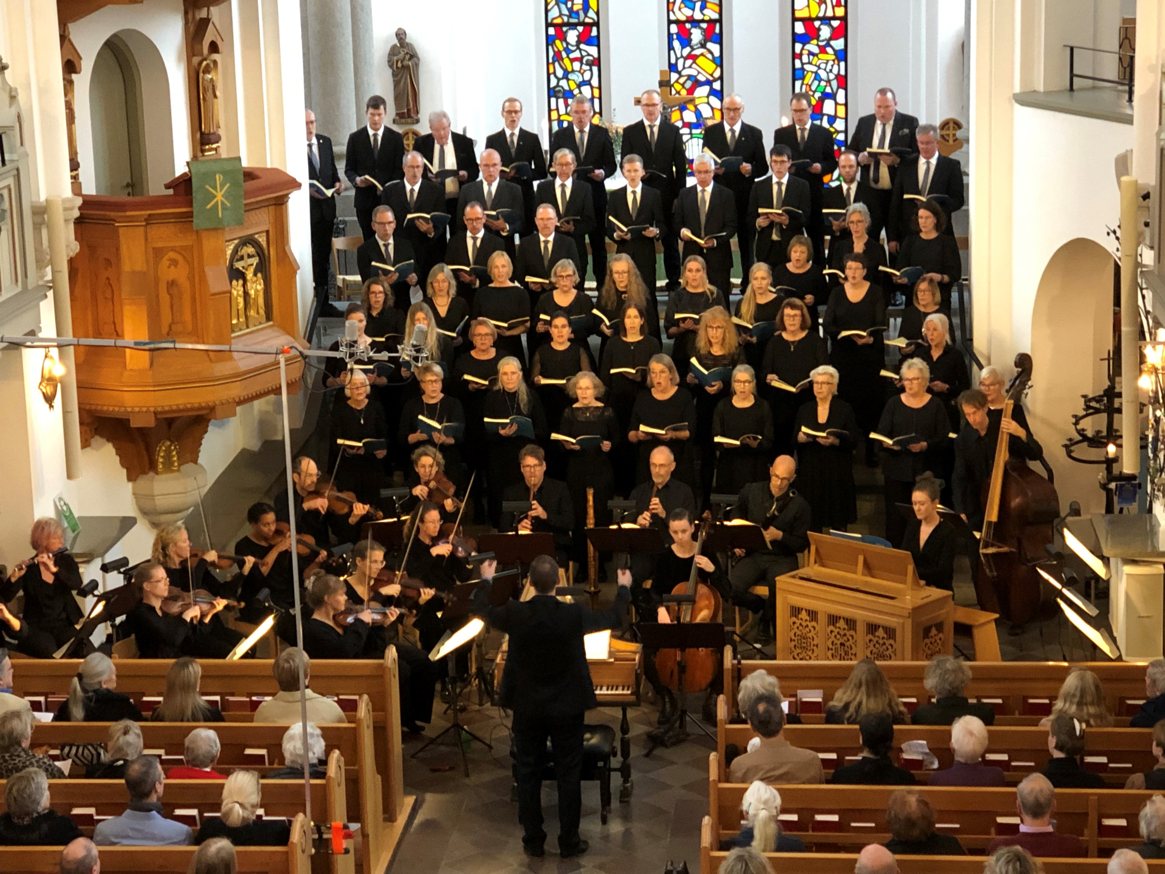 Cirka femtio svartklädda personer står i trappan upp till altaret i Hässleholms kyrka för att sjunga H-mollmässan.