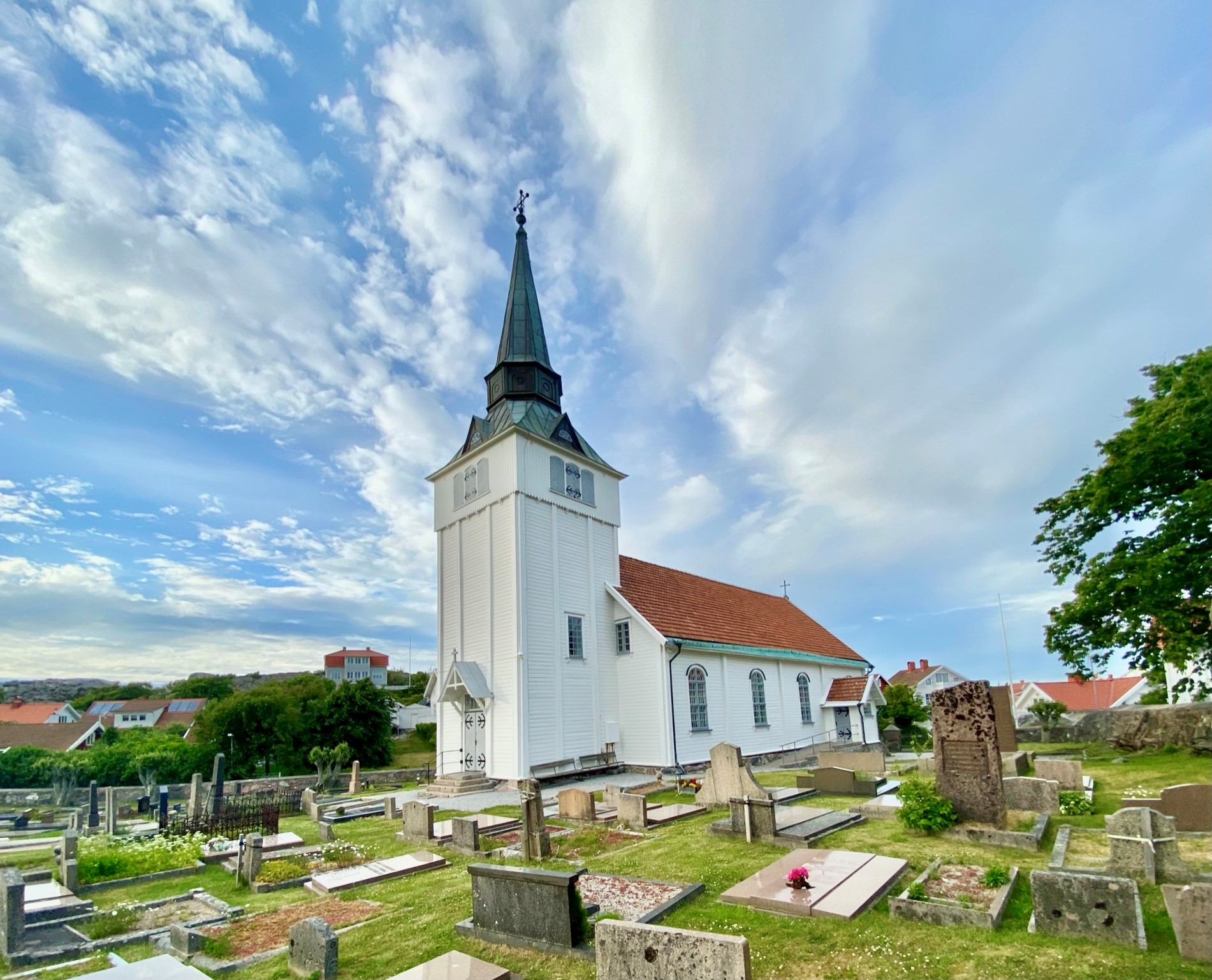 Gullholmens kyrka. På himlen bakom sveper vita moln förbi klarblå himmel.