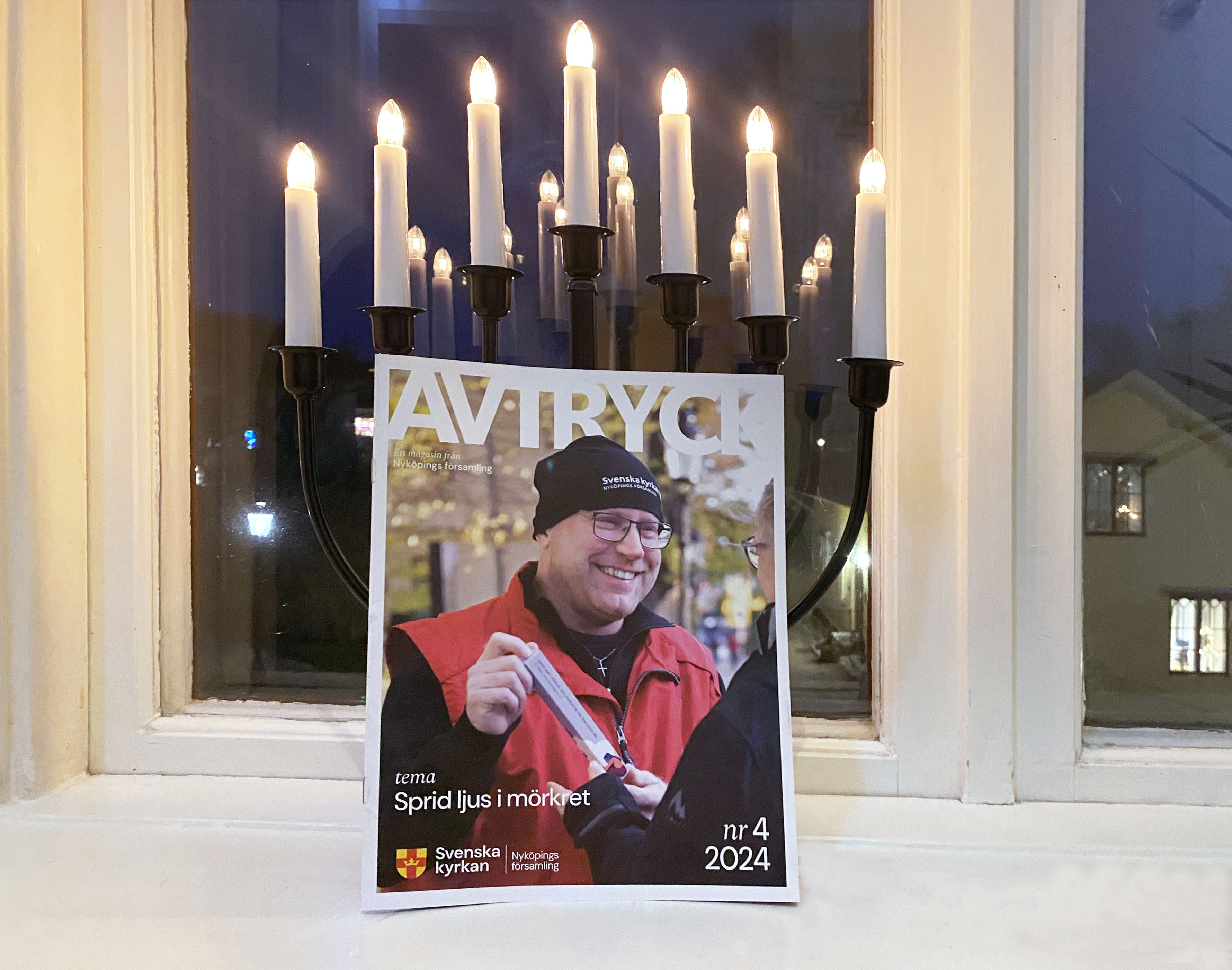 Tidningen Avtryck i ett fönster med adventsljusstake