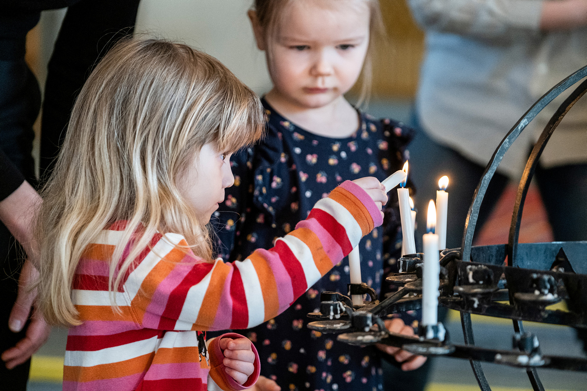 Två barn tänder ljus vid ljusbäraren i kyrkan.