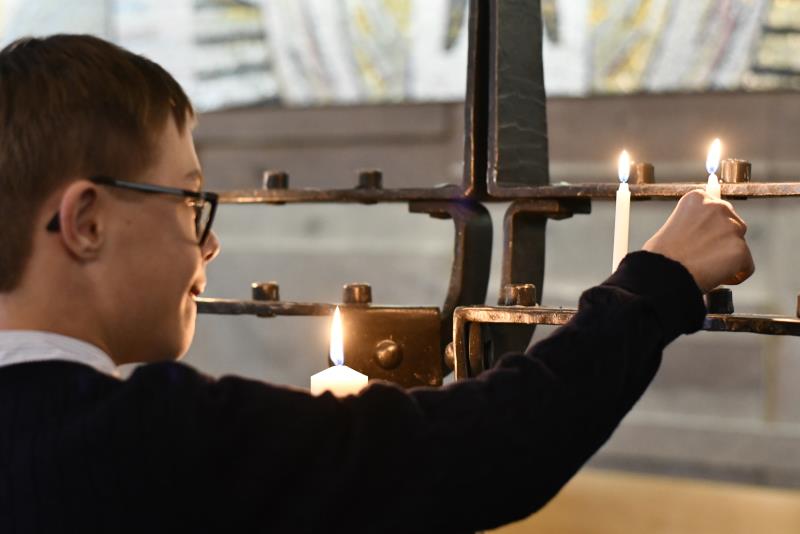 Ett barn tänder ljus och sätter i ljusbäraren i Högsbo kyrka.