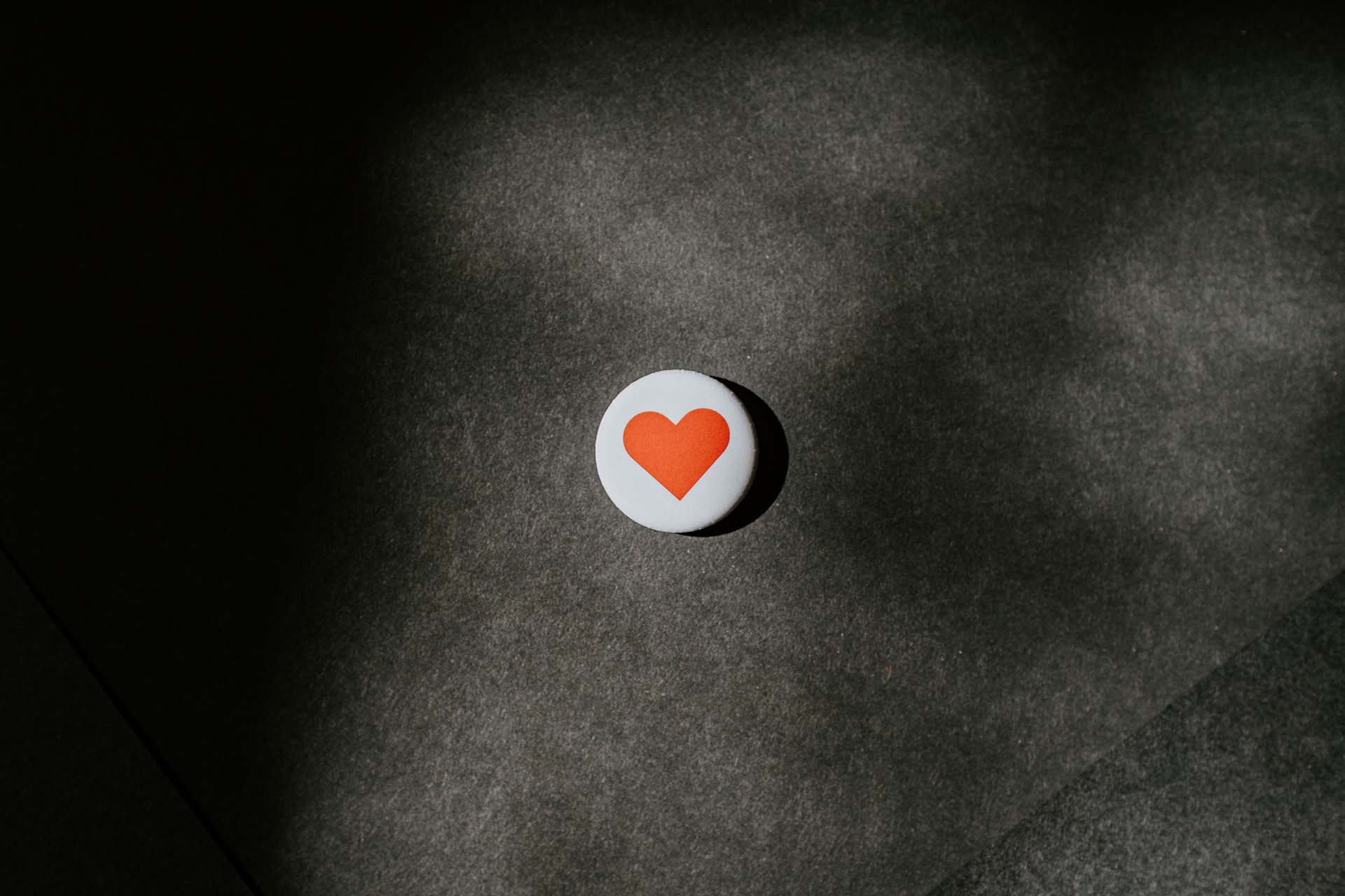 En vit sten med ett handmålat hjärta ligger mot en mörk bakgrund.