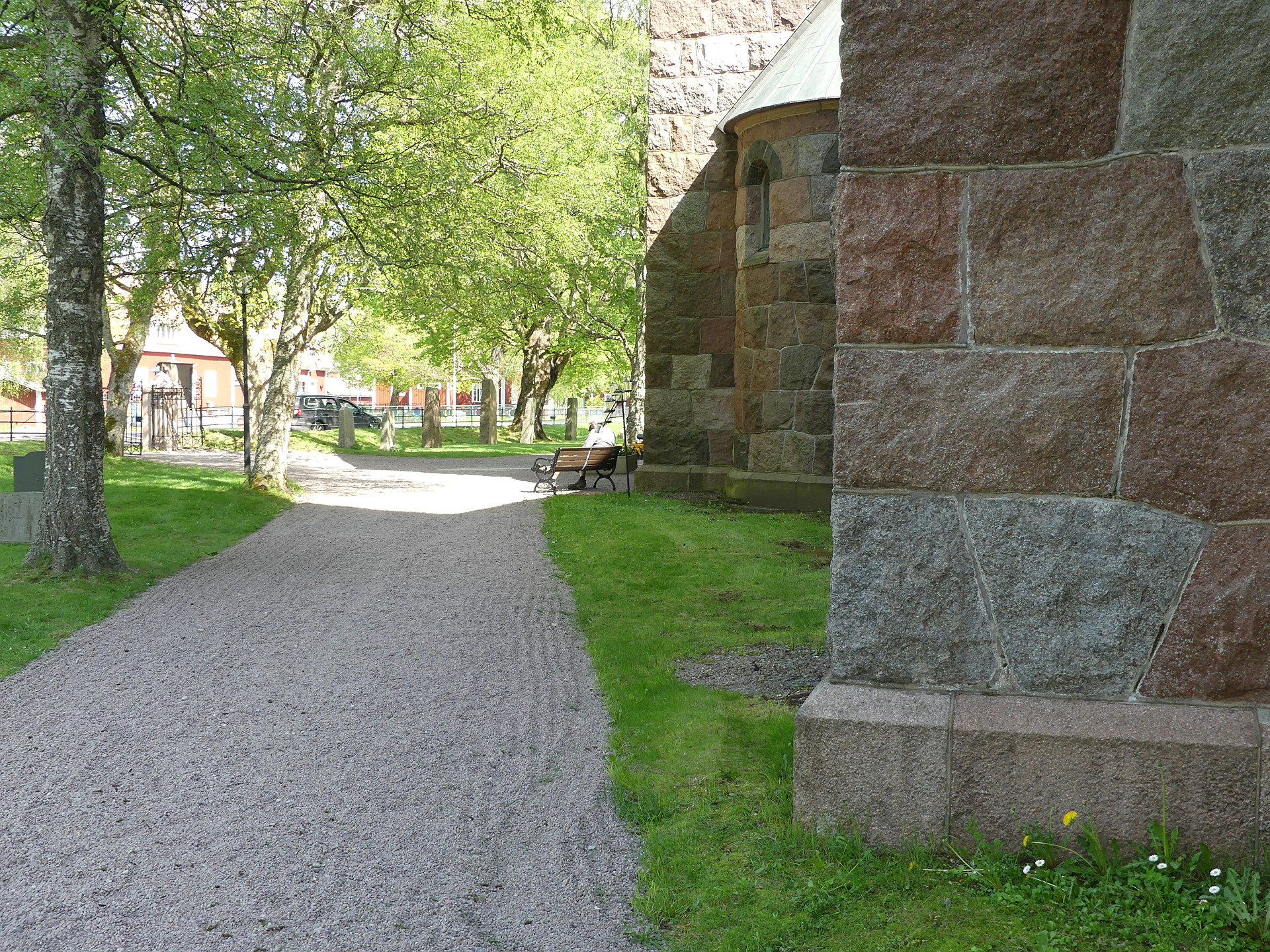 I bilden ser vi en grusgång som går förbi en kyrka, vi ser bara lite av grunden.