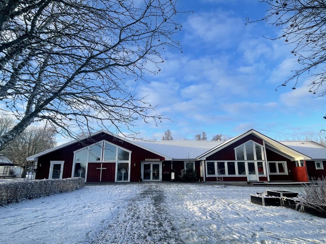 Mariakyrkan under en blå himmel med moln. Snö ligger på marken. 