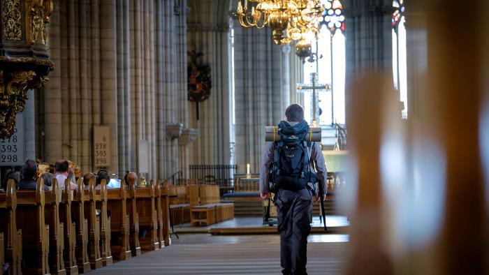 En man med ryggsäck går in i en kyrka