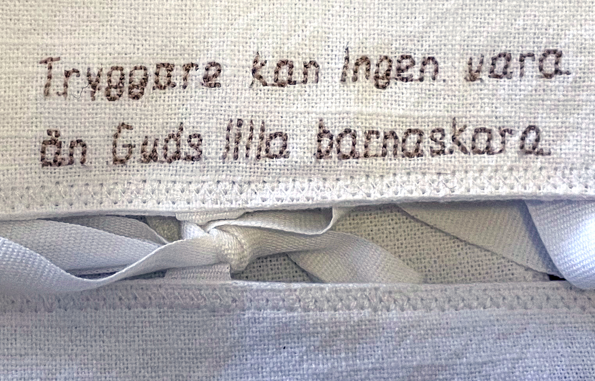 Bilde på den broderade text som finns på en dopklänning.