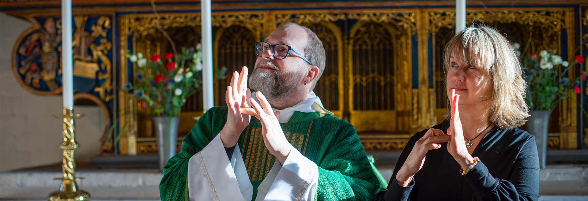 Dövpräst Johan Wisser och stiftskonsulent Åsa Grönberg står vid altare och använder teckenspråk.