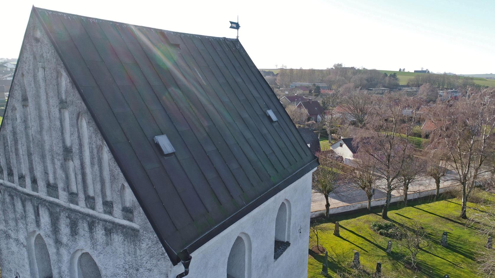 Vitkalkad kyrka med svart tak.