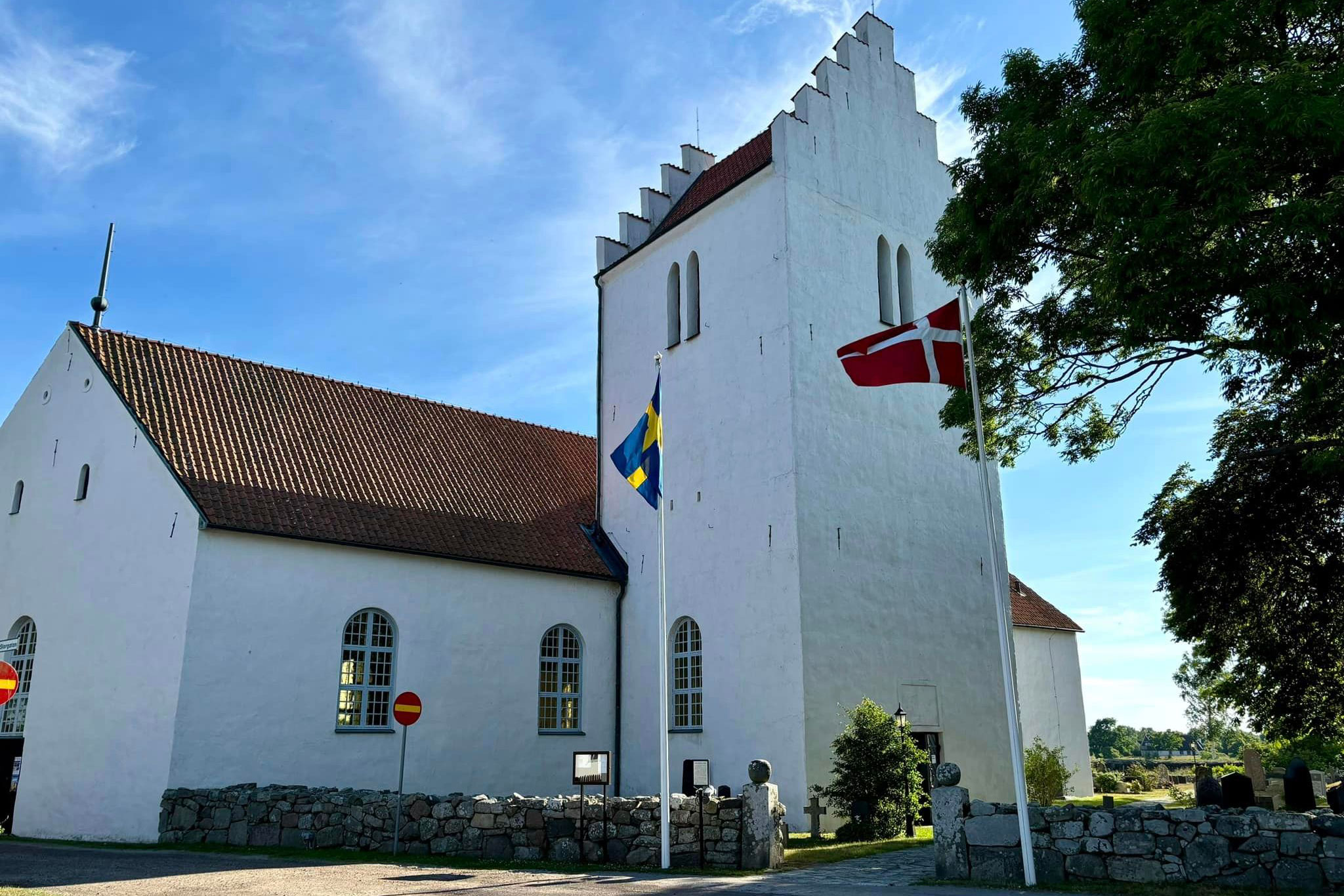 Vitkalkad kyrka med torn.