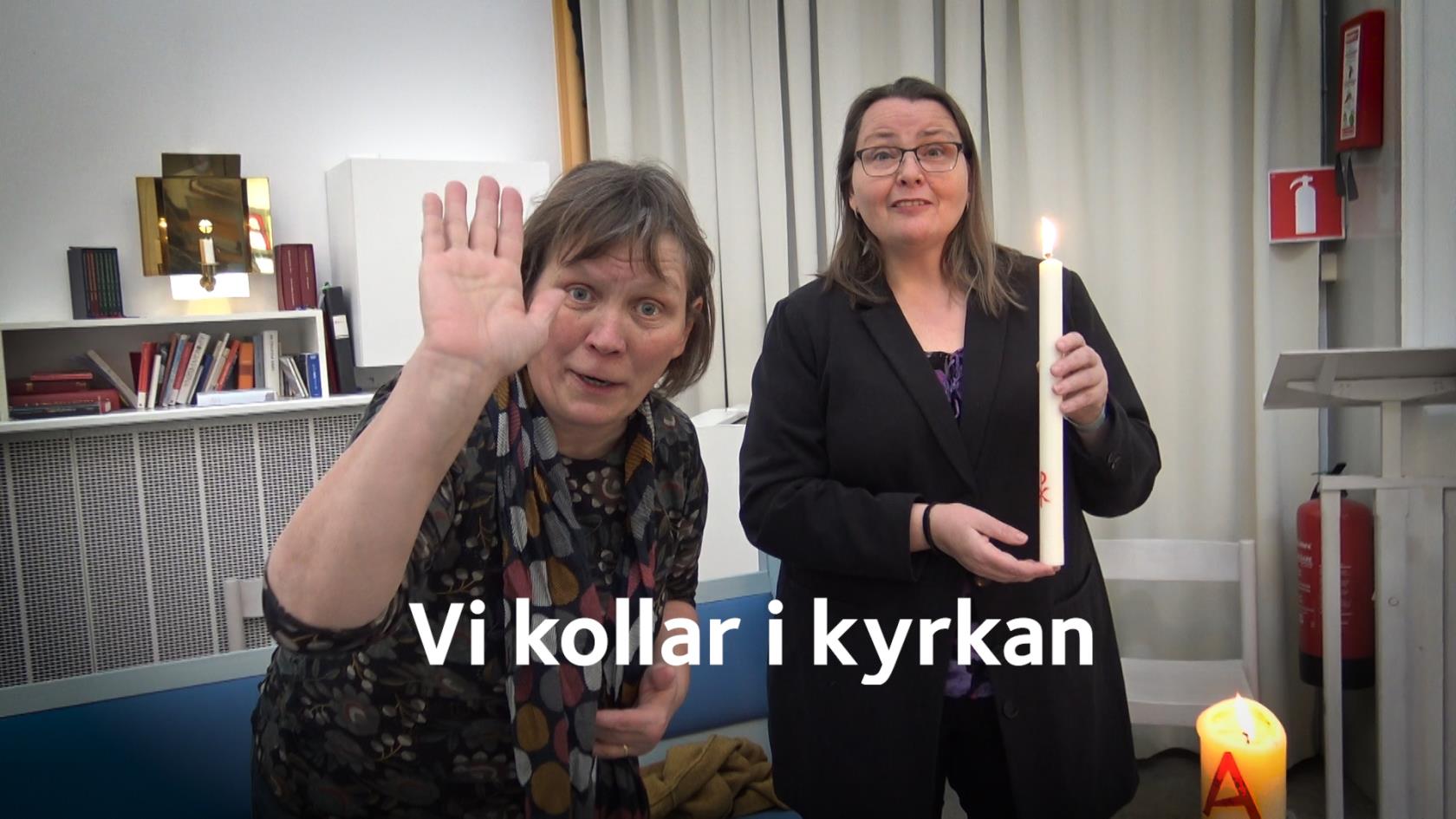 Två kvinnor står i en kyrkolokal. Den ena vinkar och den andra håller ett tänt stearinljus.