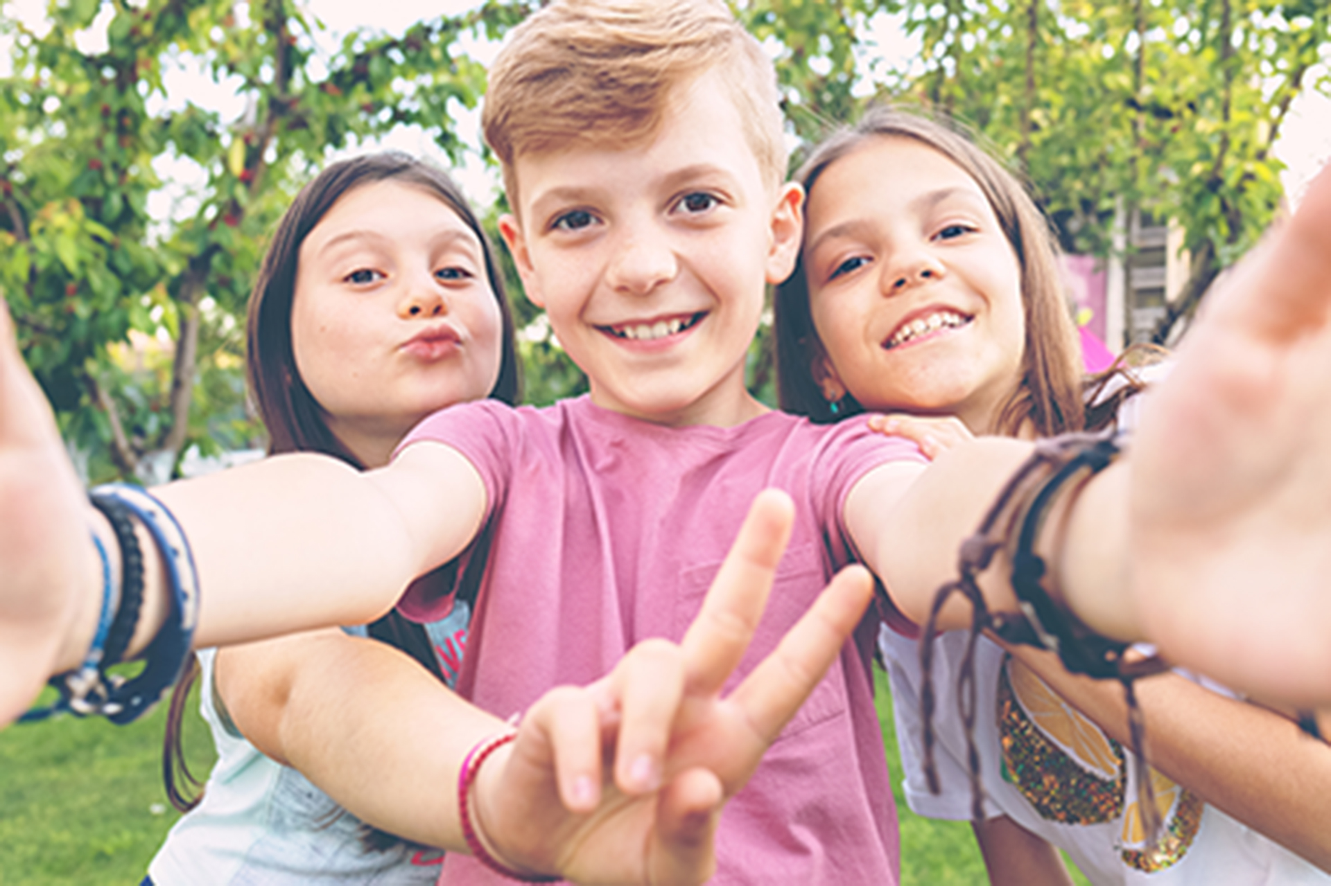 tre barn i tolvårsåldern står framför en kamera och tar en selfie.