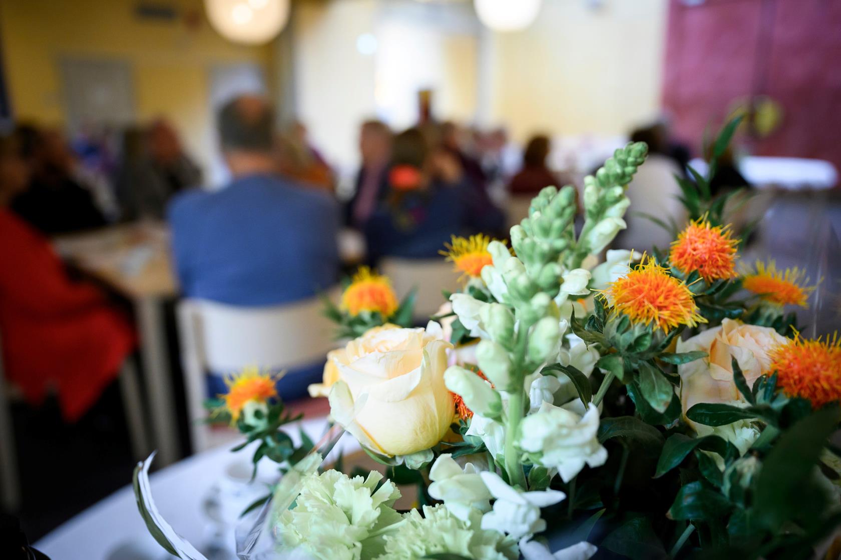 Människor i samtal, blommor på bord