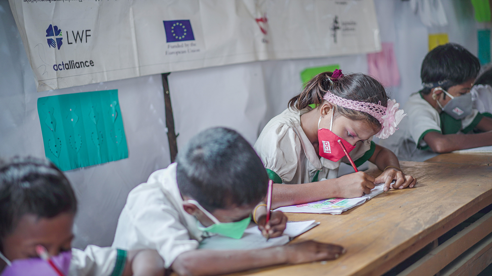 Skrivande barn i skolbänk i Myanmar