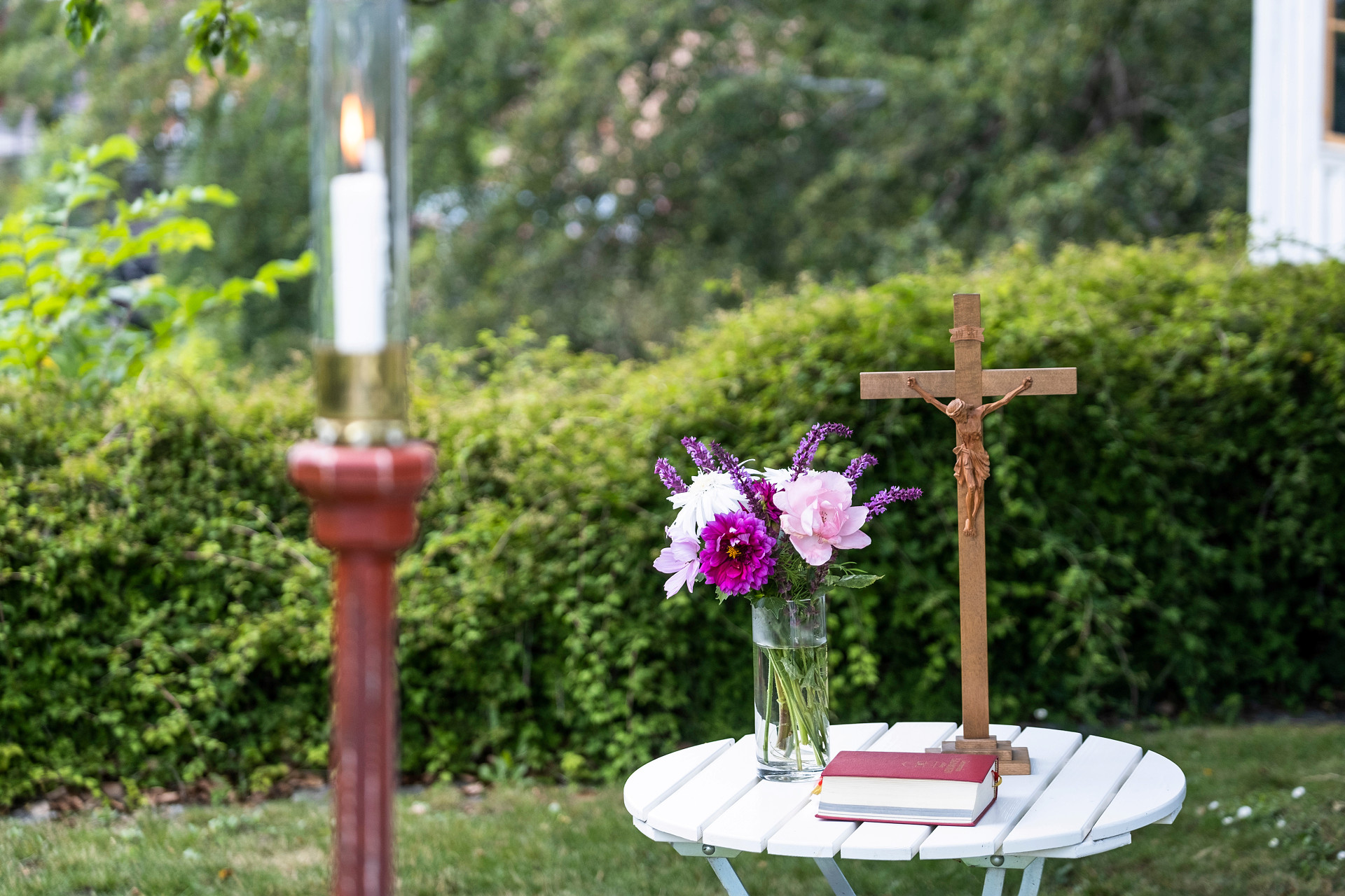 ljus, blommor och kors på utomhusbord