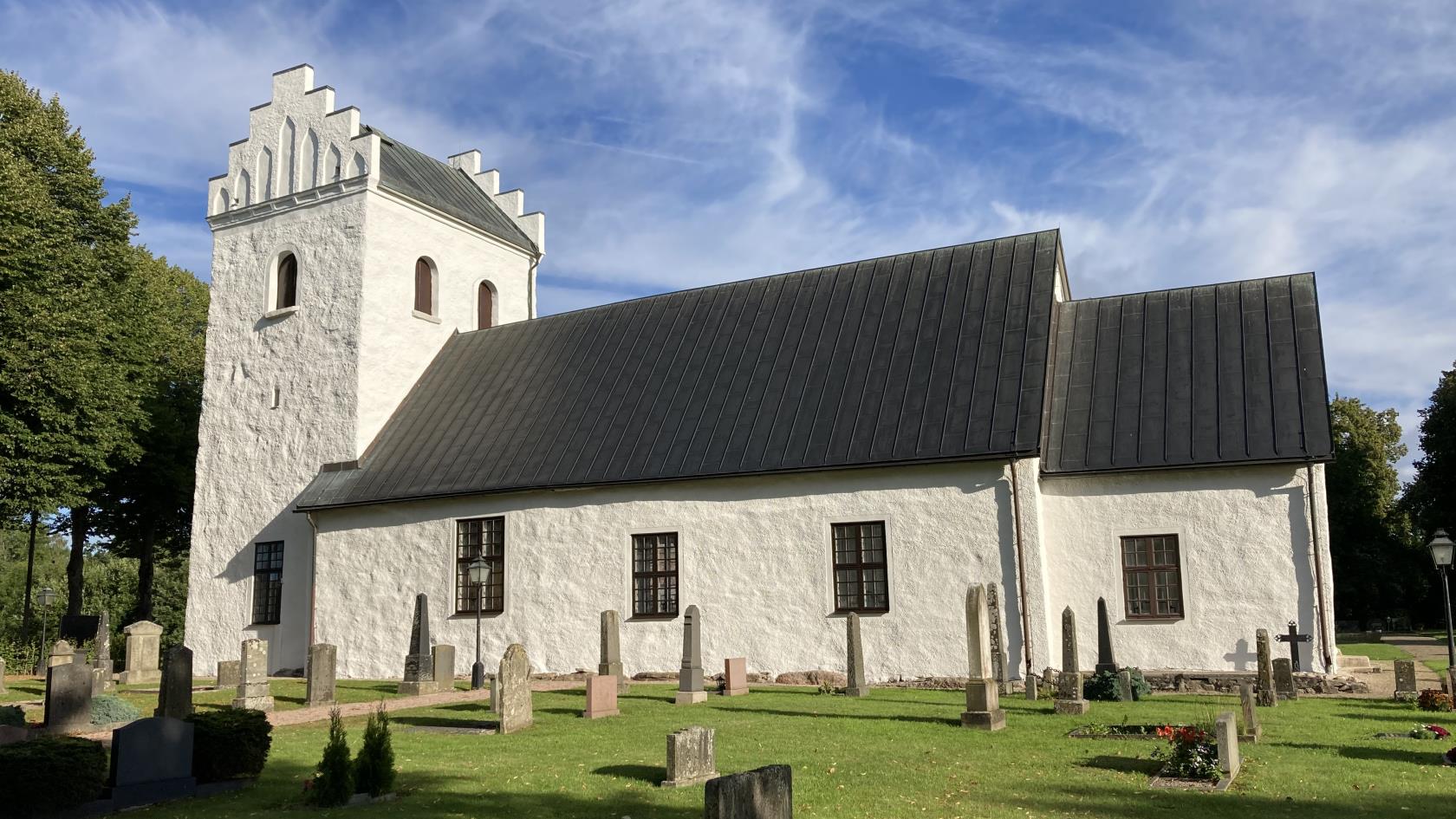 Vitkalkad kyrka mot blå himmel.