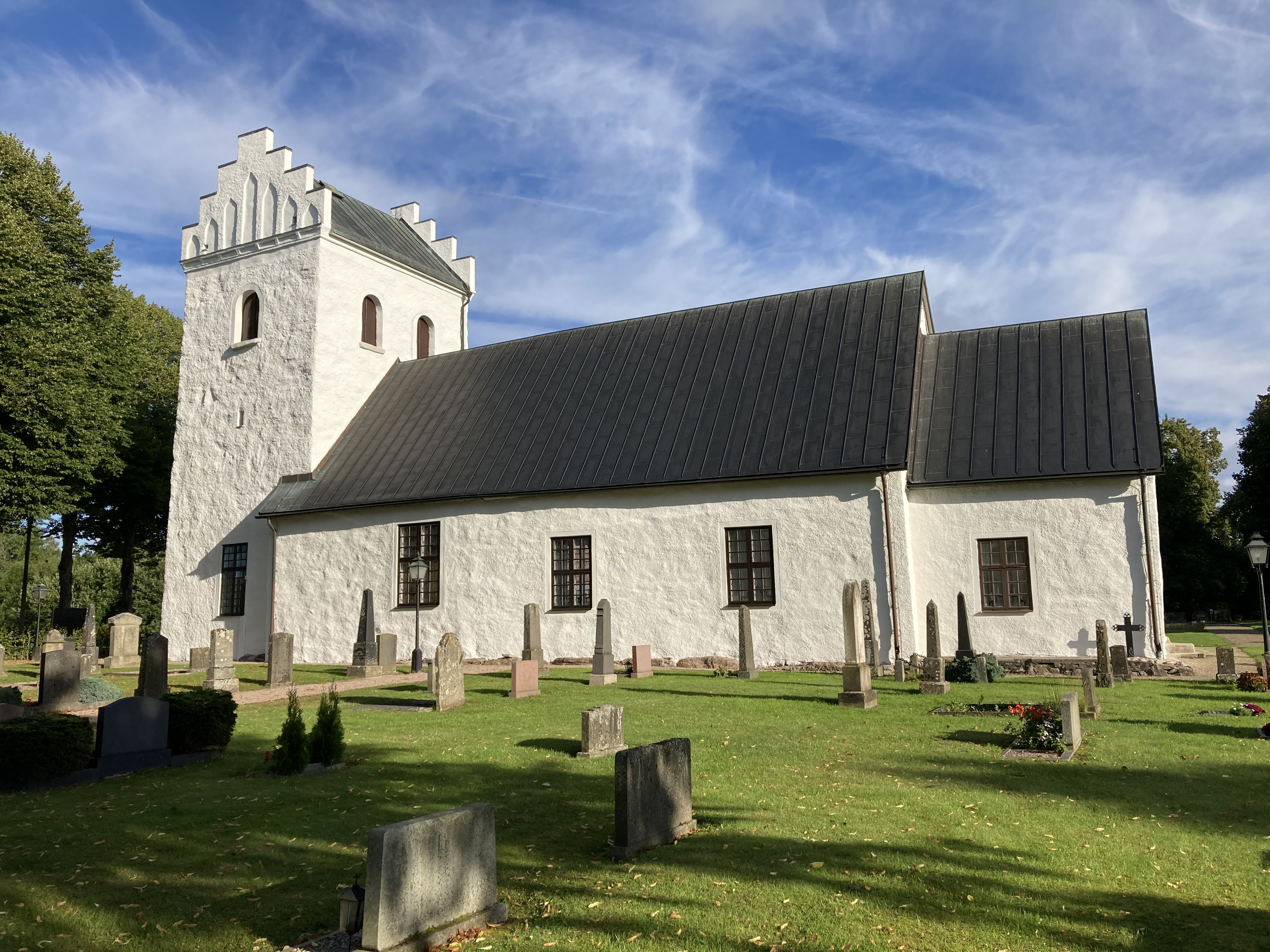 Vitkalkad kyrka mot blå himmel.