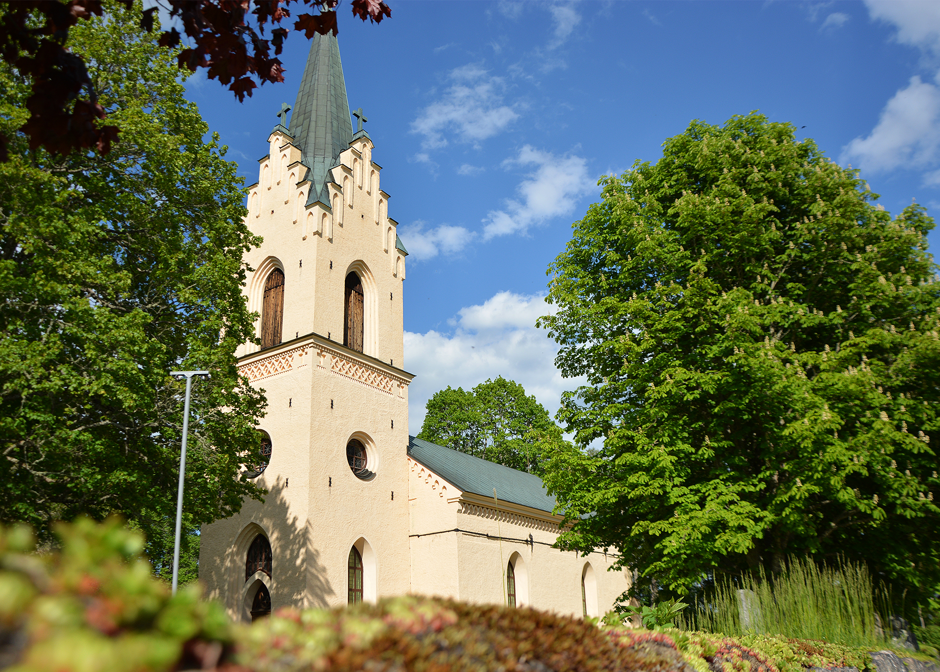 Enåkers kyrka mellan grönskande träd.