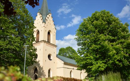 Enåkers kyrka mellan grönskande träd.