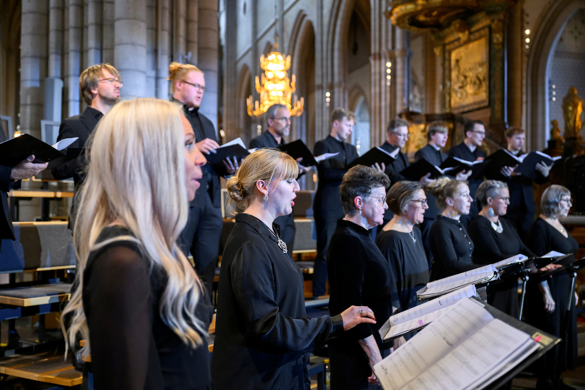 Kvinnor och män som sjunger i kör i Uppsala domkyrka. Enhetligt svartklädda framför de sång under Kyrkomusiksymposium 2022. 