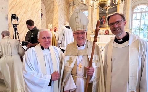 Tre vitklädda präster står framför ett altare och ler mot kameran: förre kyrkoherden i Gamla Uppsala församling, Per Anders Sölvin, nyvigda biskopen Anti Toplaan och nuvarande församlingsherden i Gamla Uppsala Andreas Holm.