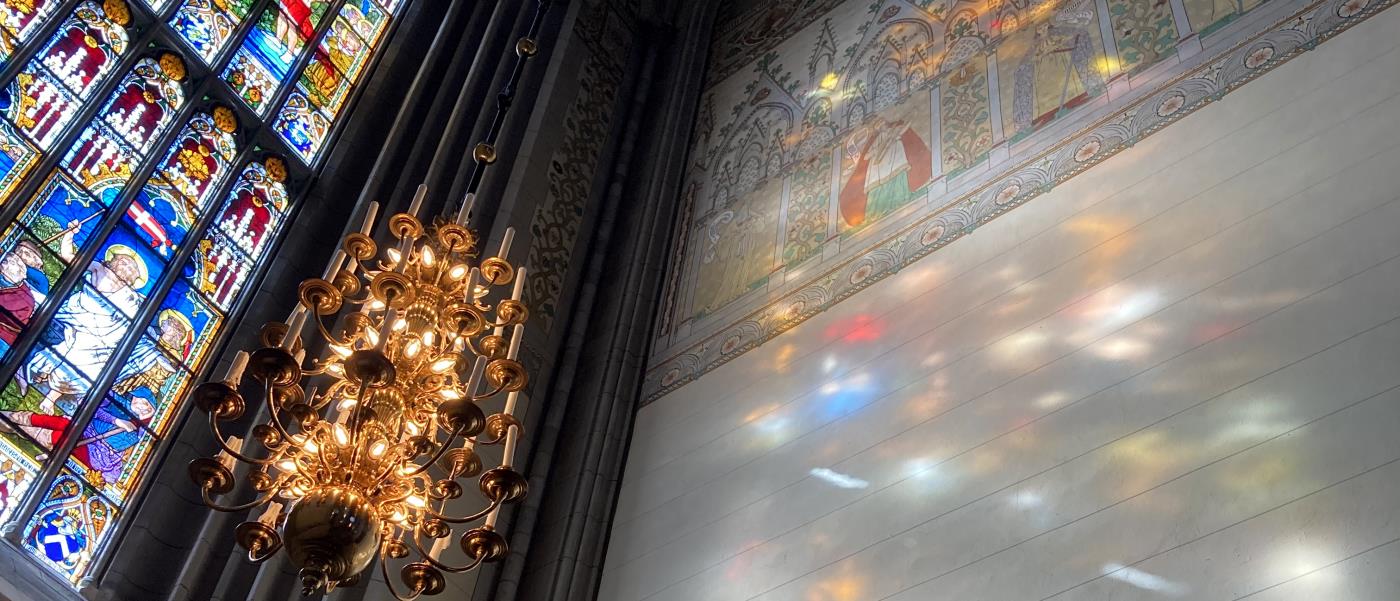 Domkyrkans södra fönsters målningar avspeglar sig i klara färger i solreflexerna på södra korets vägg.