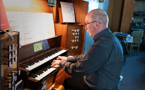 Organisten Roland Östblom sitter vid en orgel och spelar.