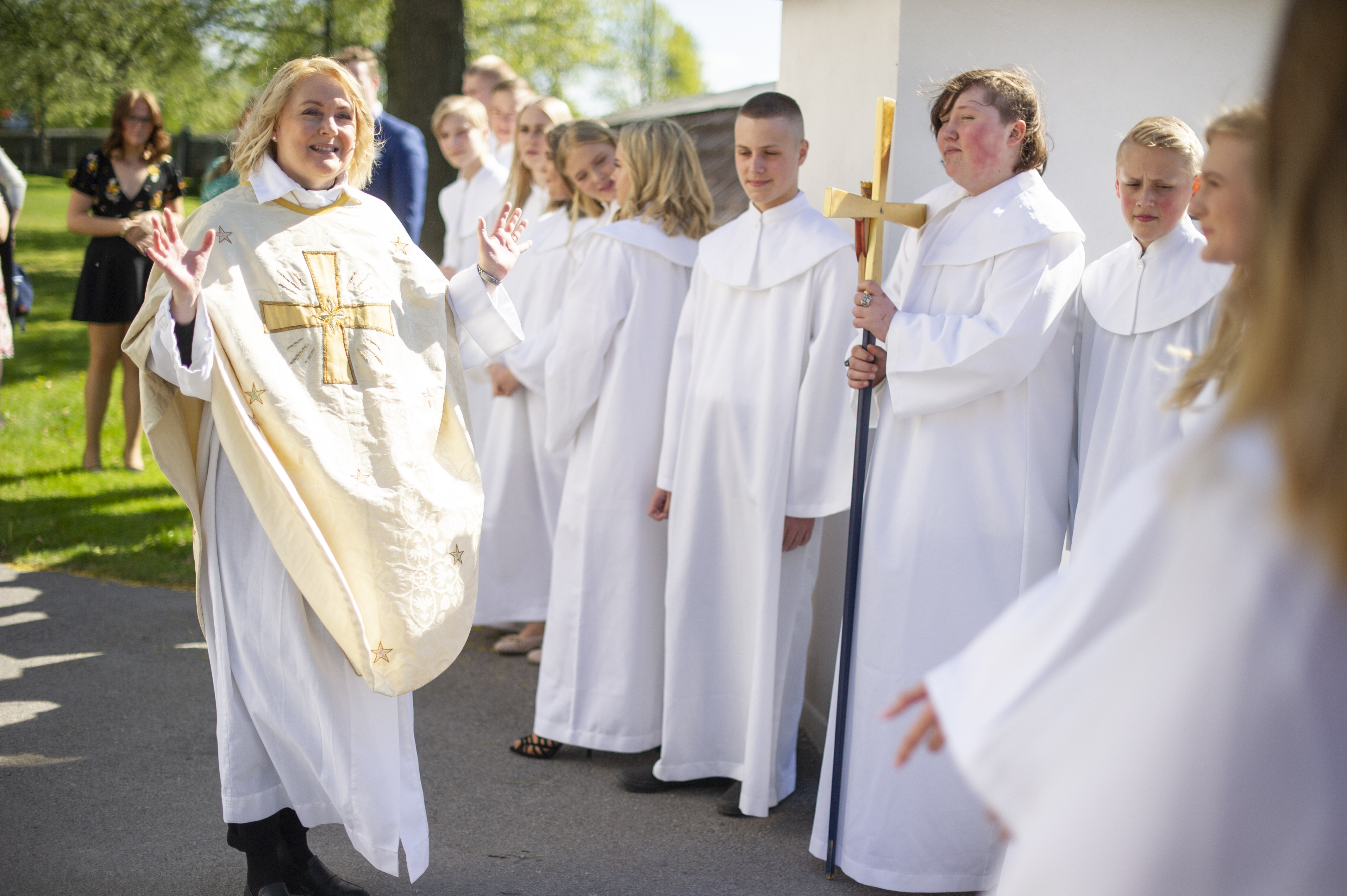 En präst hälsar på en konfirmand utanför en kyrka