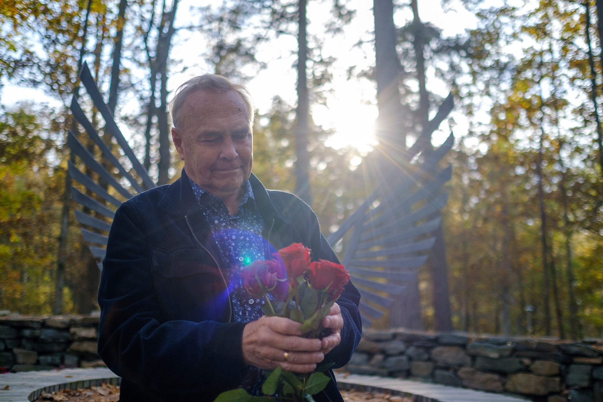 Rune Johansson med ett fång rosor i famnen vid Ekgläntans askgravplats.