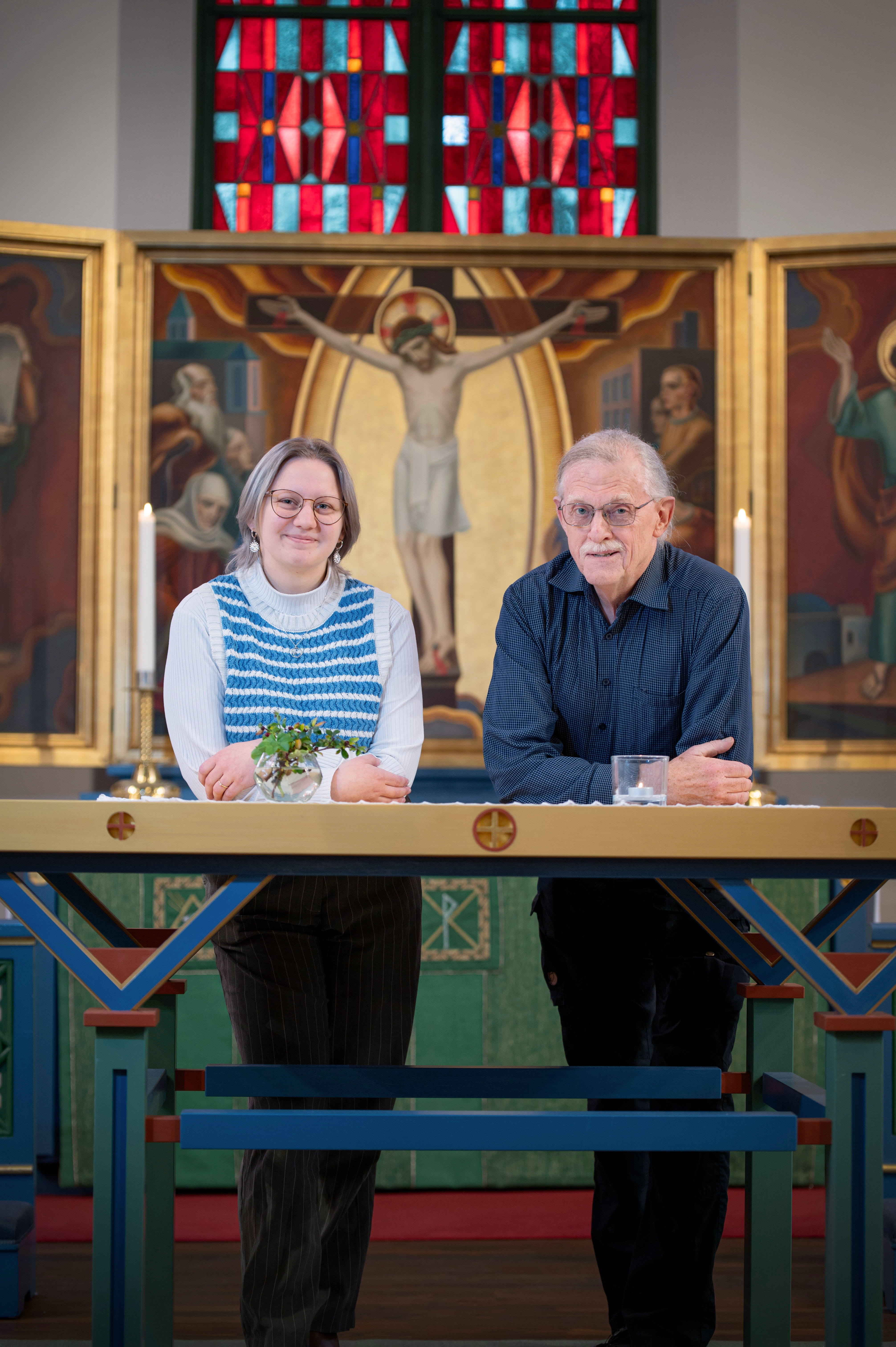 Kyrkvärdarna Amanda och Dennis framför altartavlan i Trollhättans kyrka