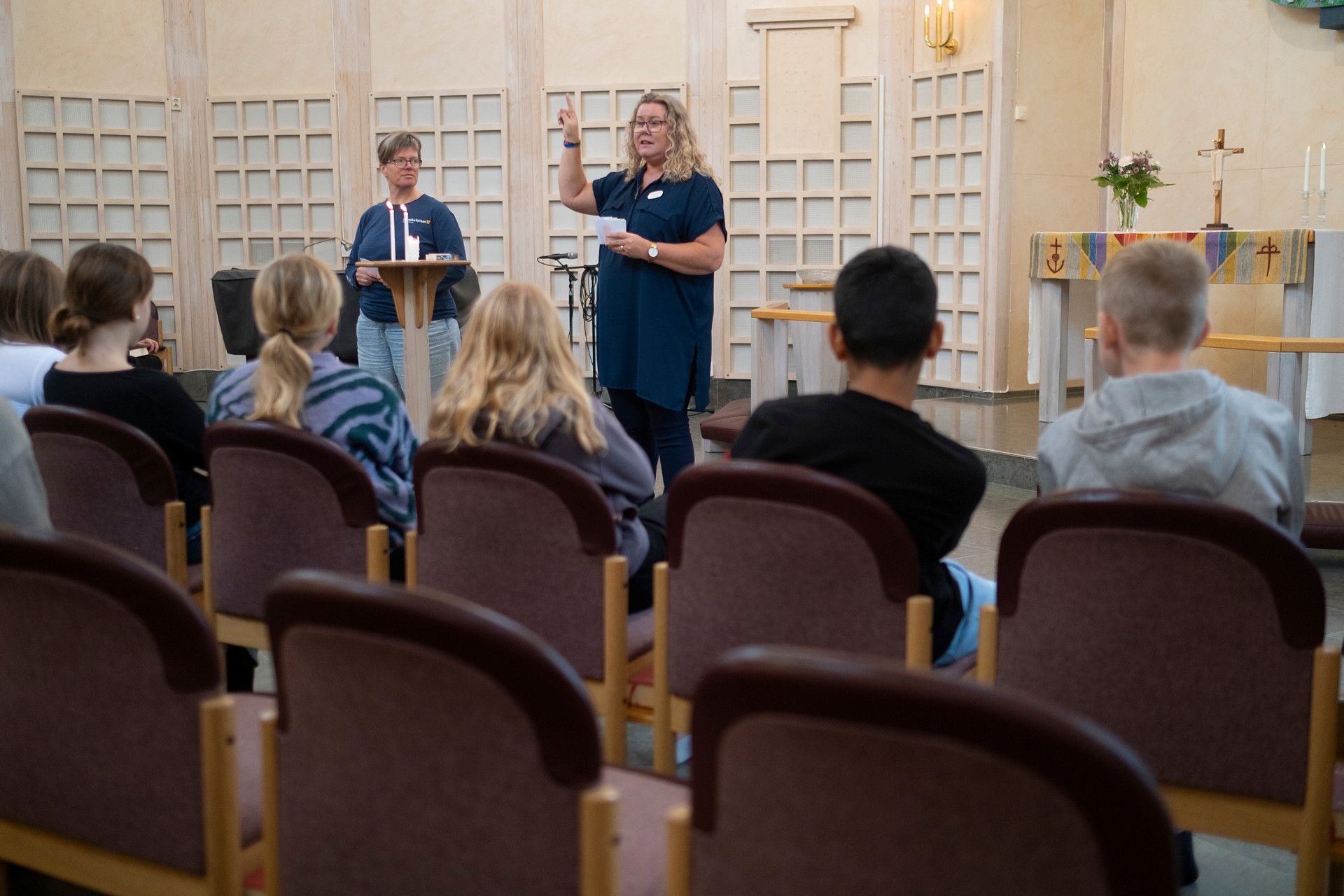 Anette och Anna pratar med en skolklass i Skogshöjdens kyrka