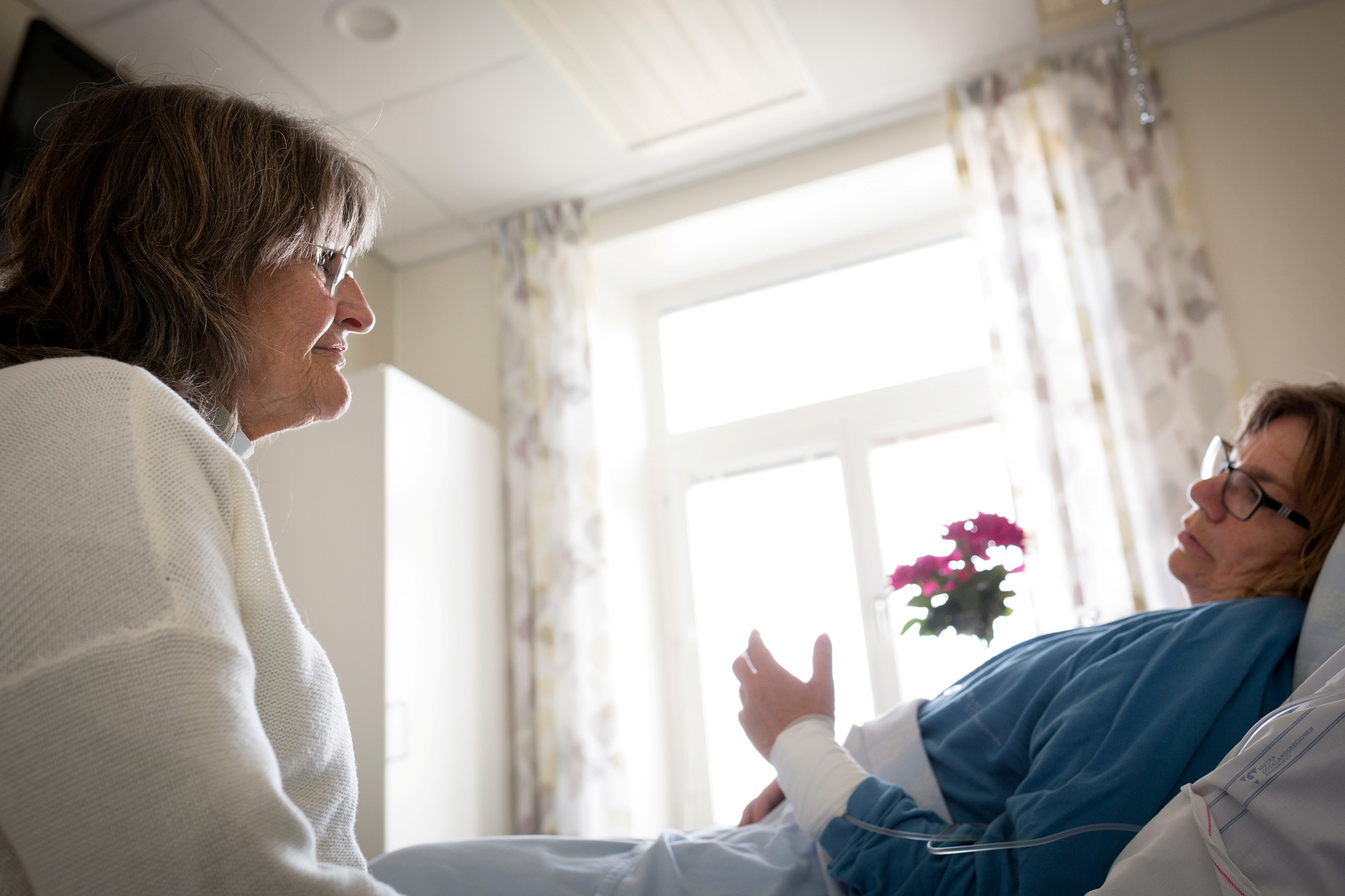 En diakon pratar med en patient på sjukhus.