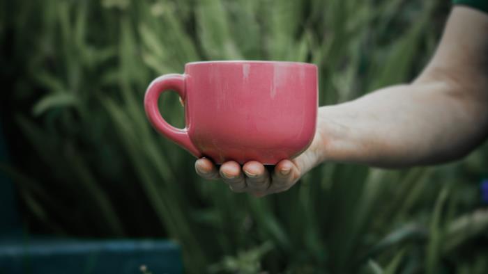 En hand håller fram en kaffekopp