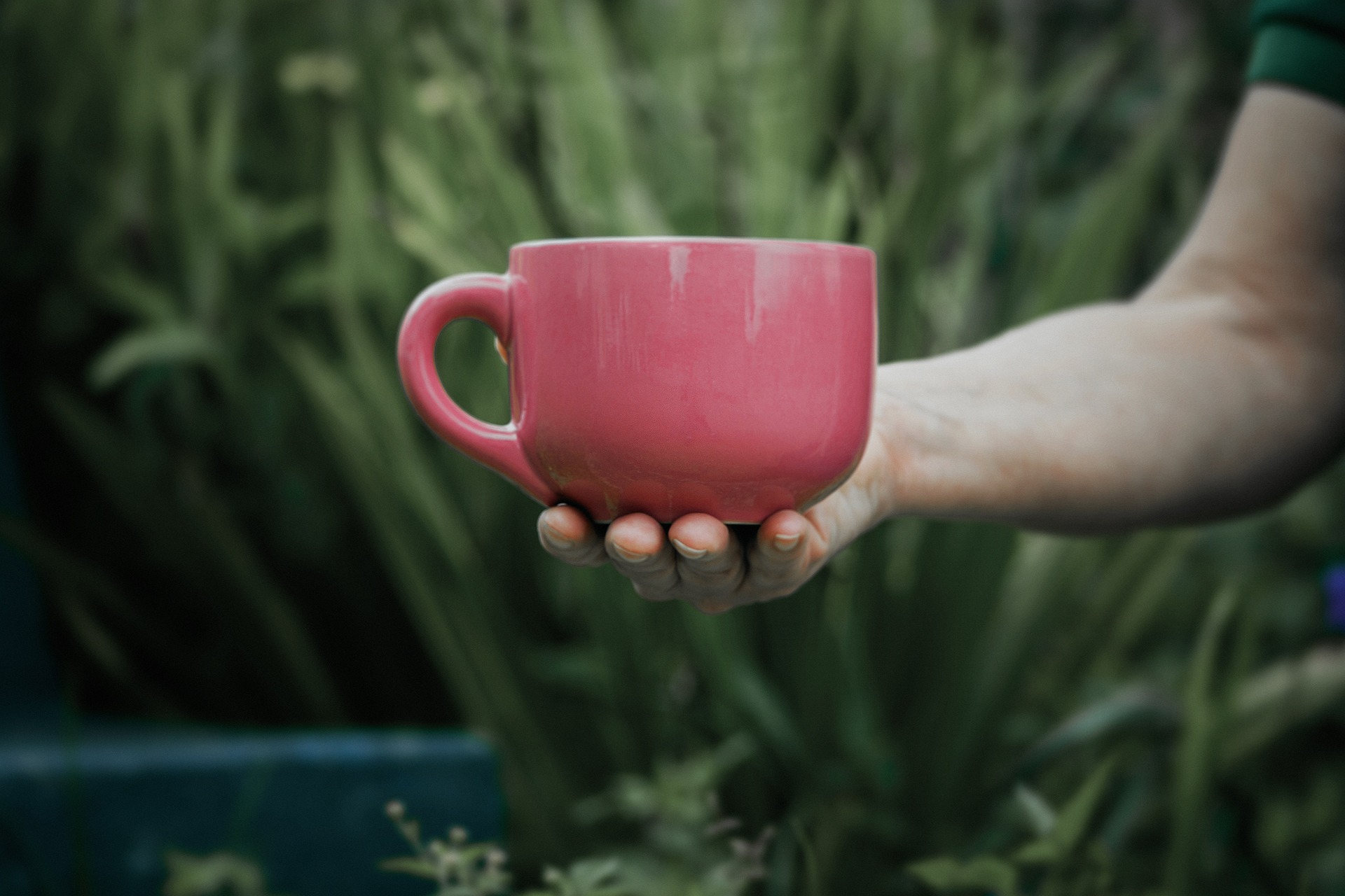 En hand håller fram en kaffekopp