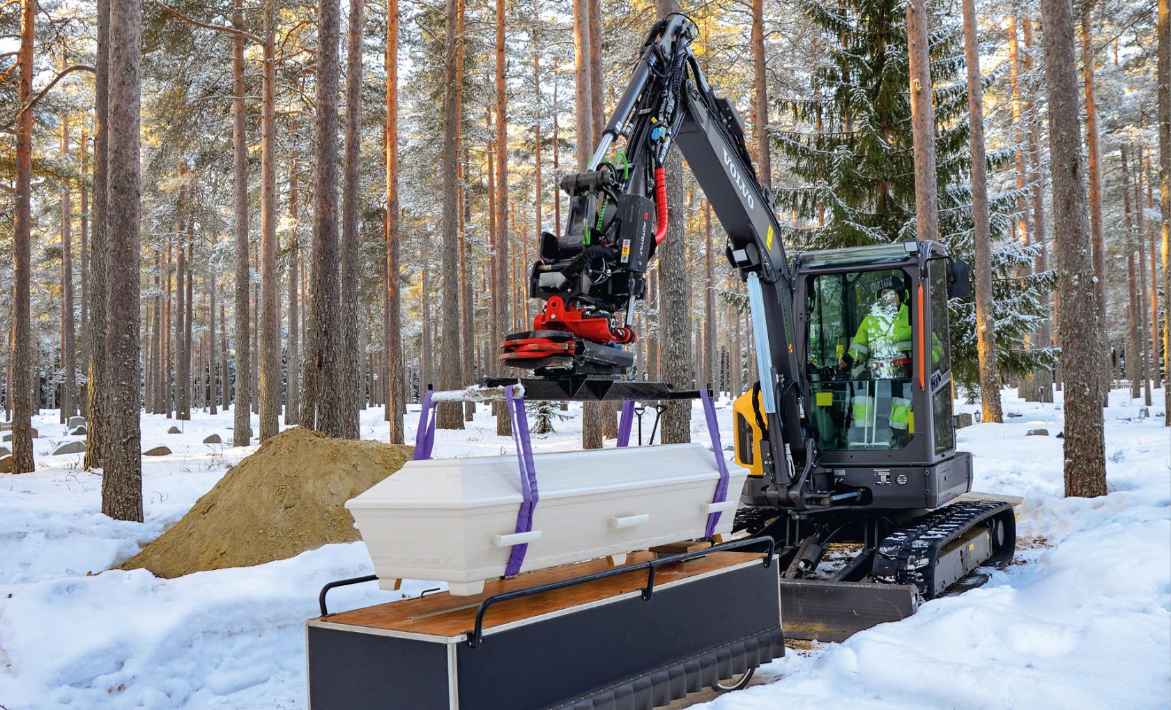 En kista ska sänkas ner i graven med hjälp av en maskin