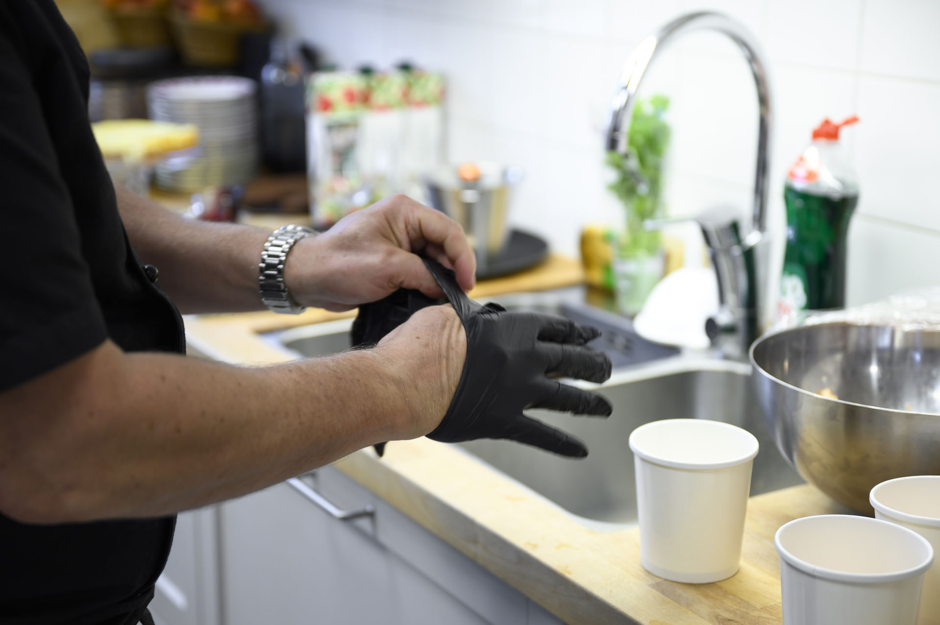 En person vid en diskbänk sätter på sig tunna plasthandskar. 