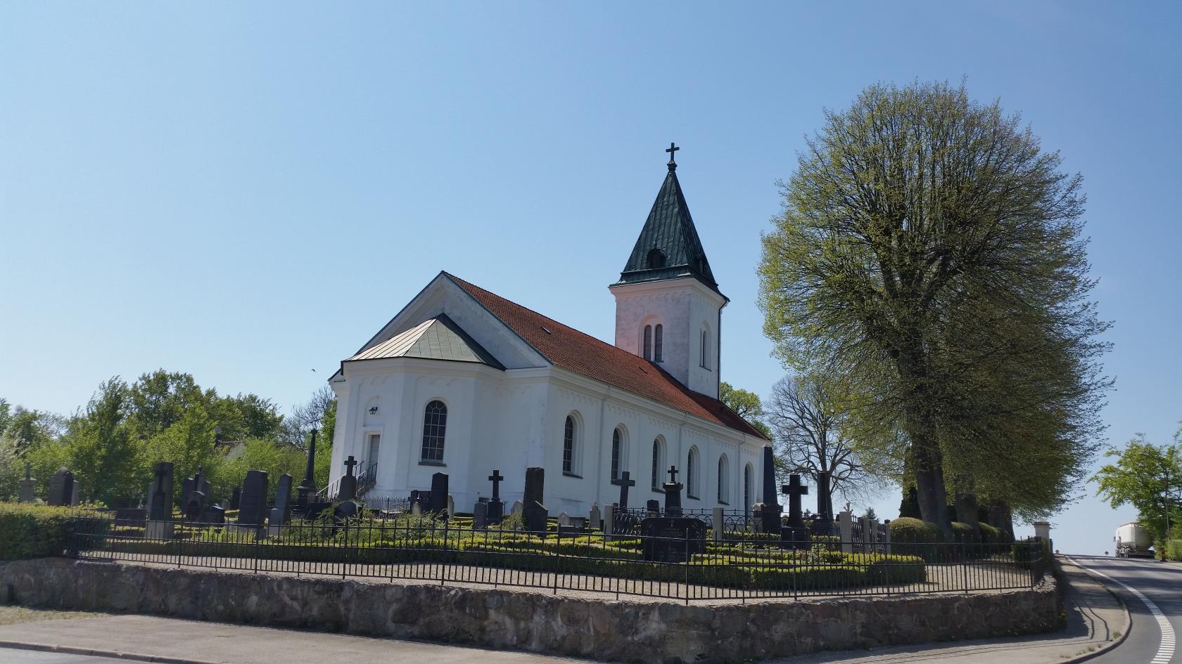 Vit kyrka med torn och rött tegeltak.