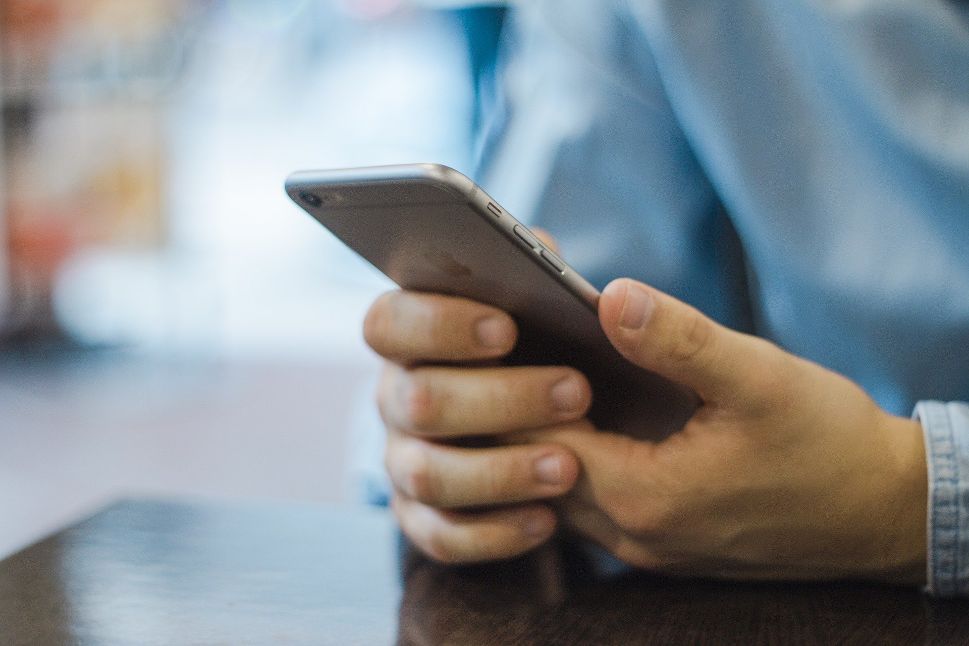 Närbild på manshänder som håller i en mobiltelefon