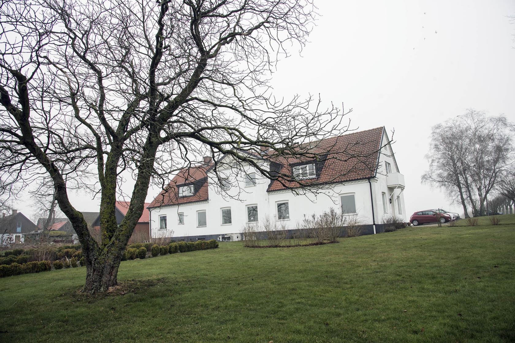 Bilden föreställer ett stort vitt hus med rött tegeltak.