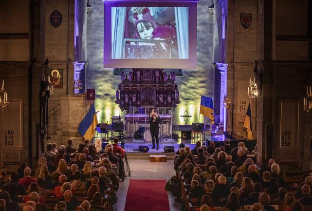 Bilden visar en artist längst fram i S:t Nicolai kyrka och kyrkbänkar fulla med folk.