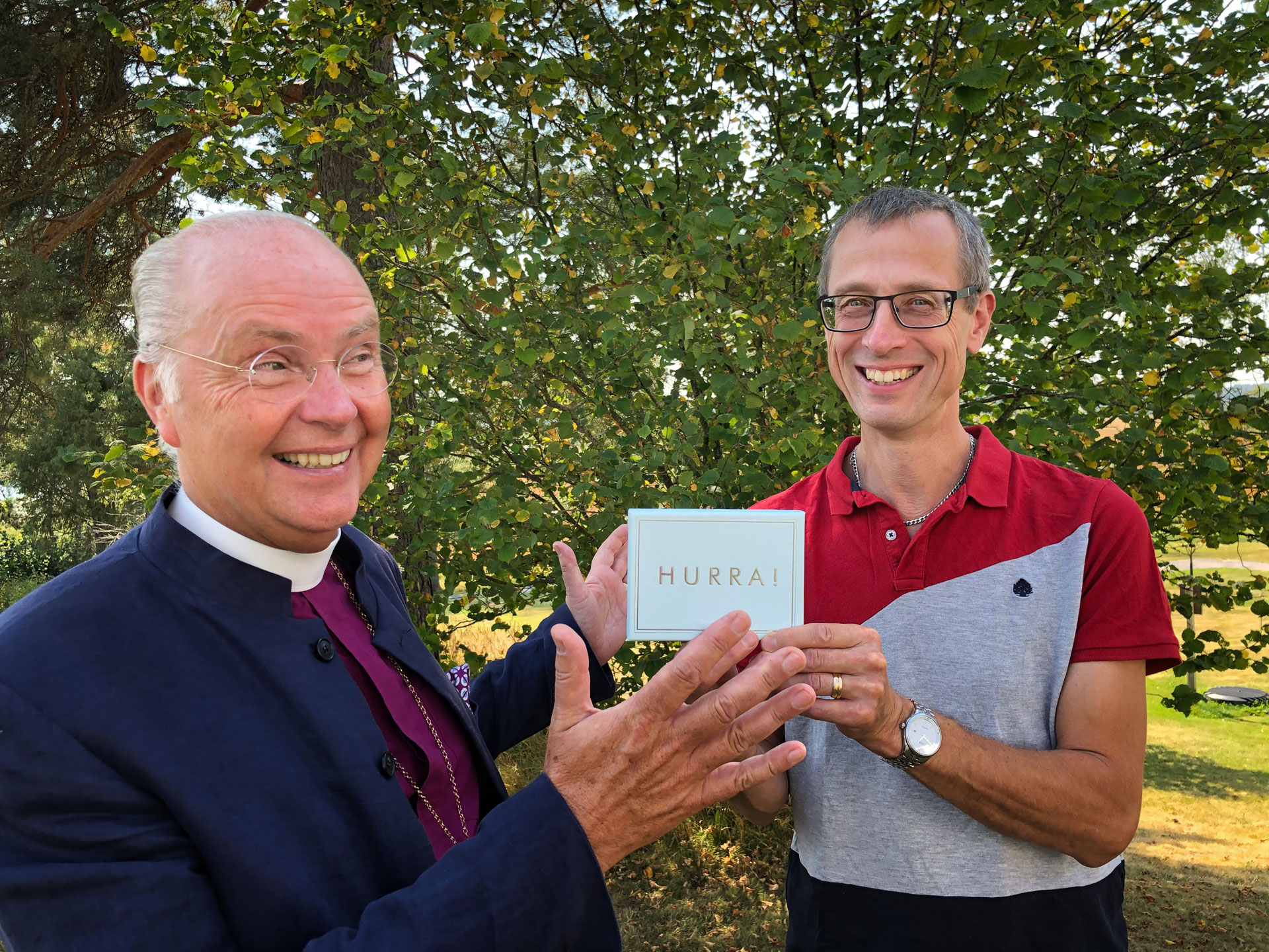 Bilden visar biskop Johan Dalman som räcker över ett grattiskort till kyrkomusiker Mats Bertilsson