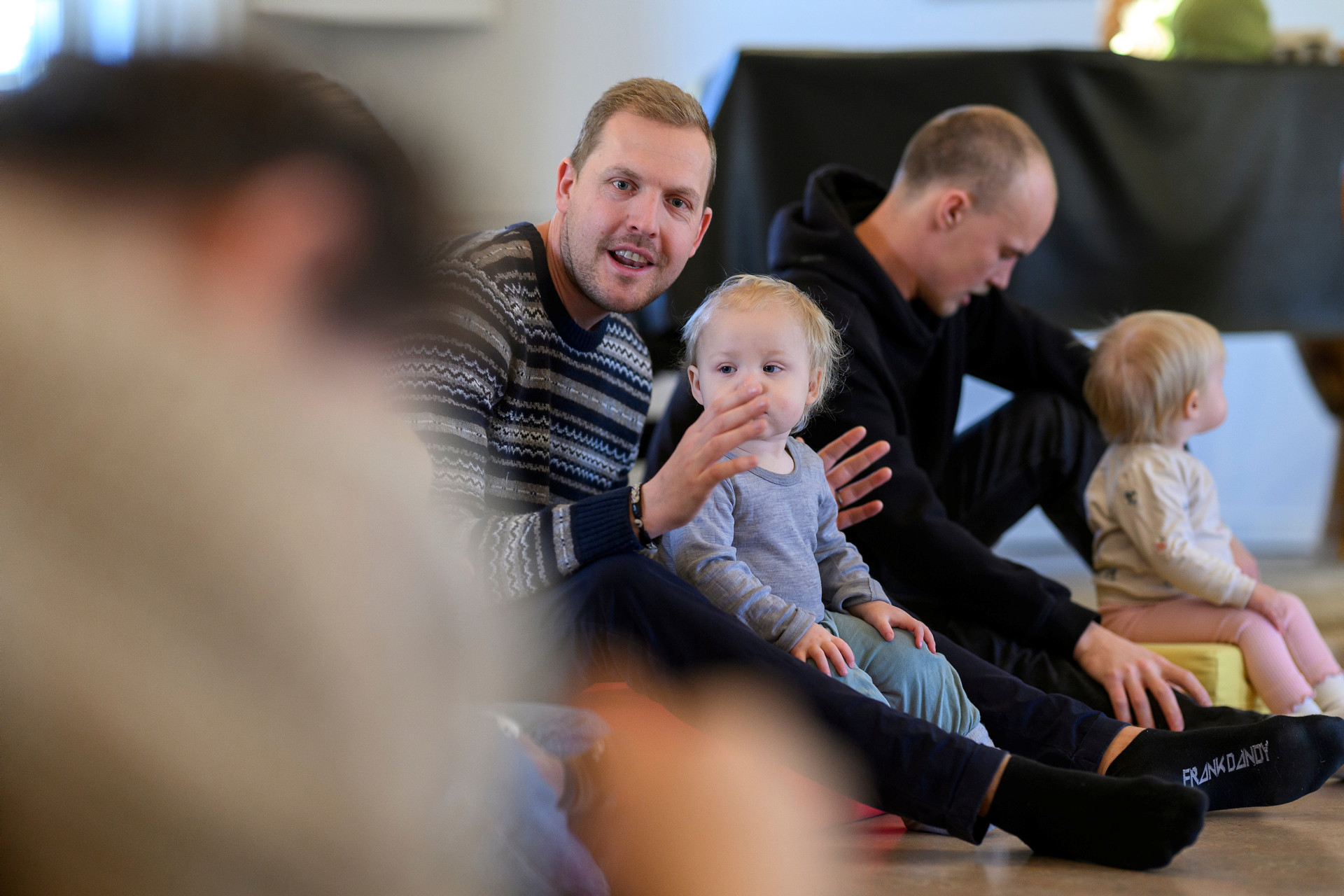 Föräldrar och småbarn sitter ner tillsammans.