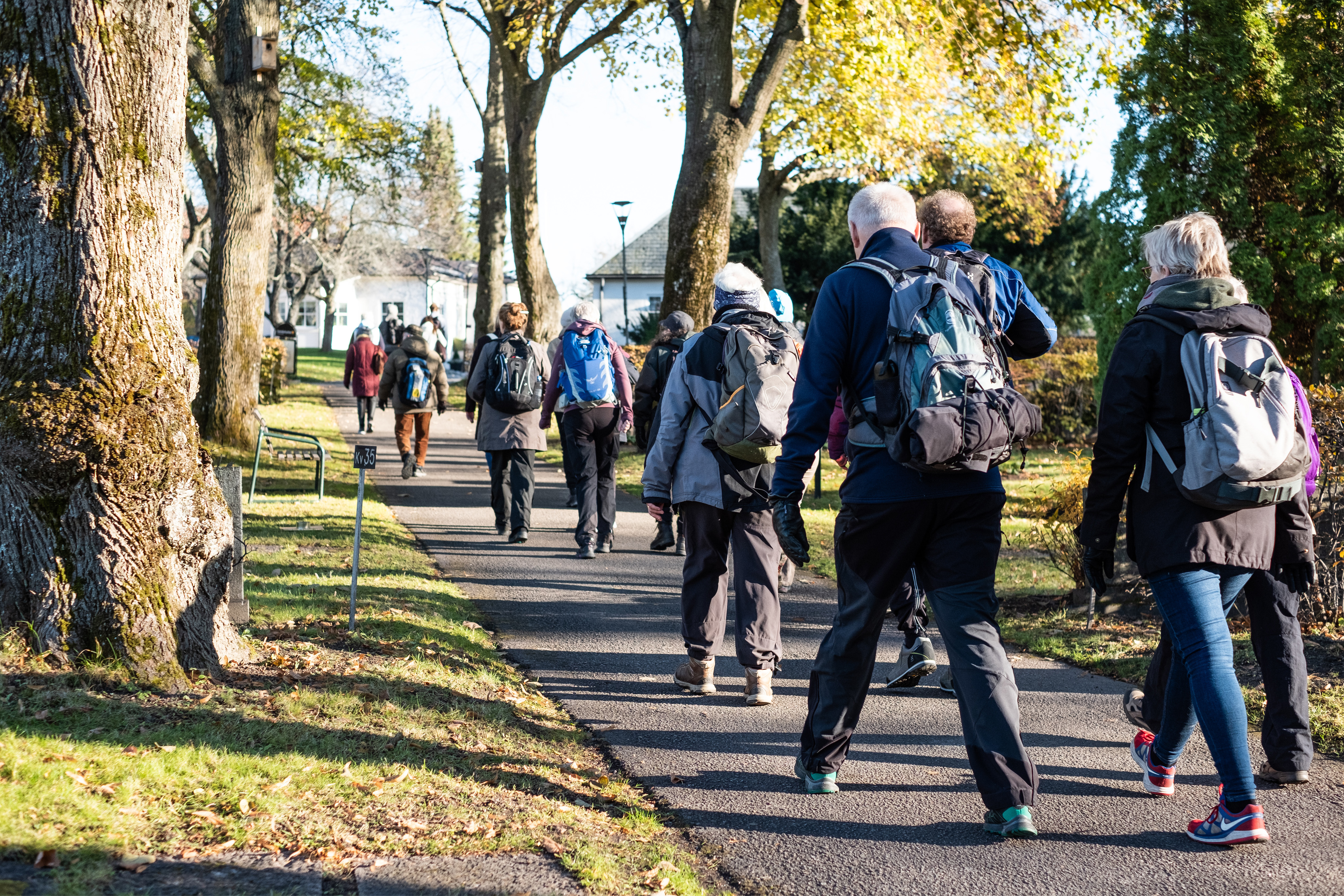 Grupp människor i fritidskläder går i en park.