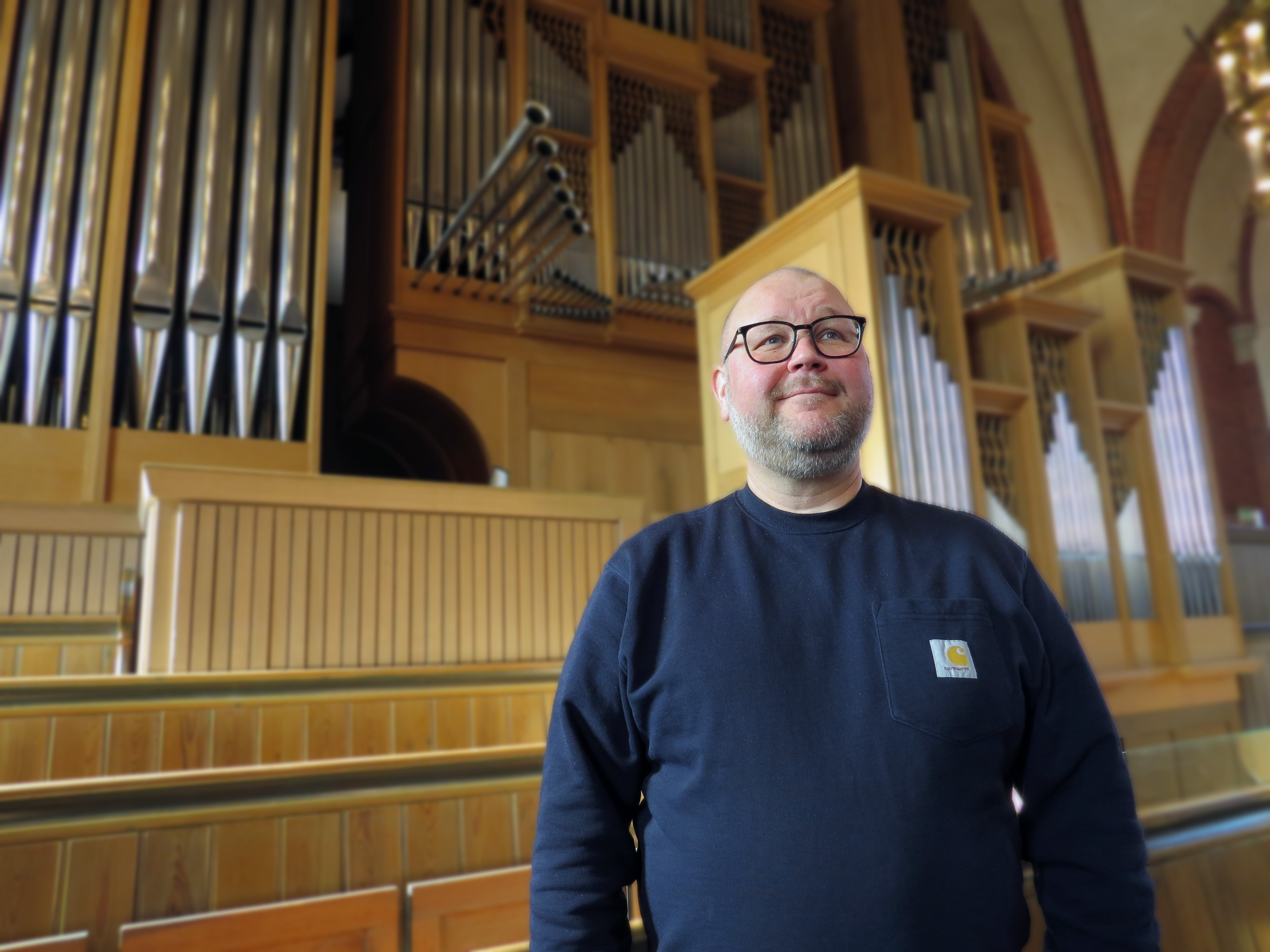 Glad man framför stor orgel.