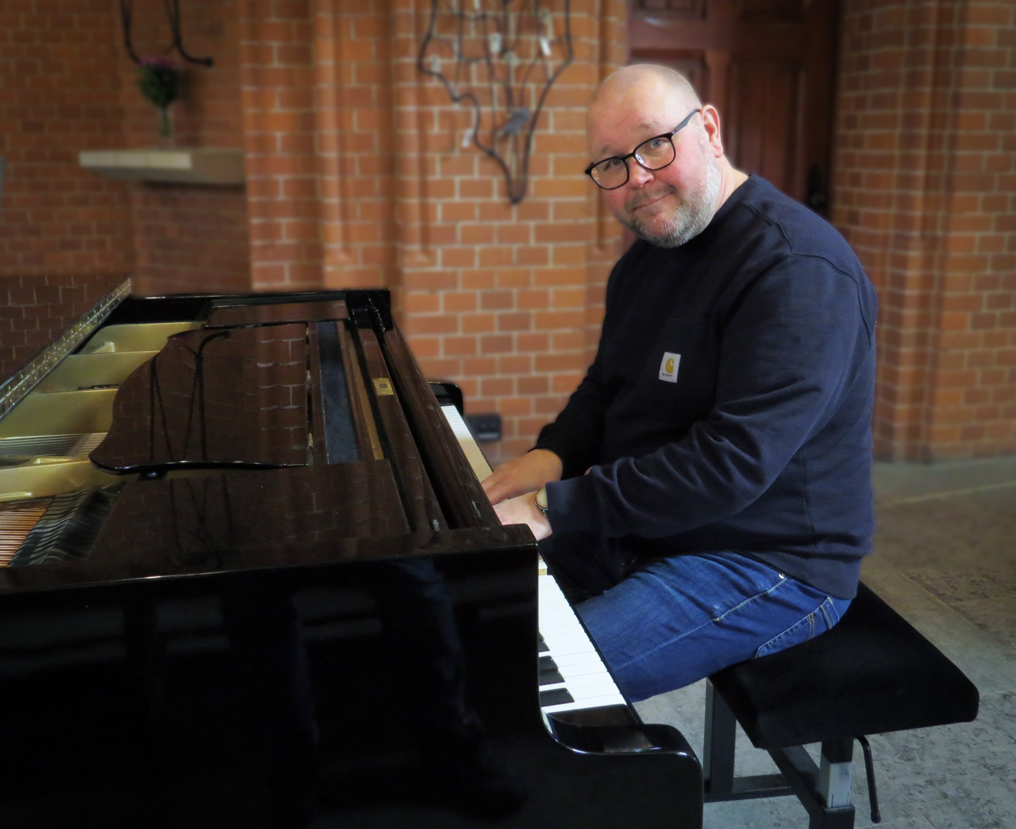 En man spelar på flygel i kyrka.