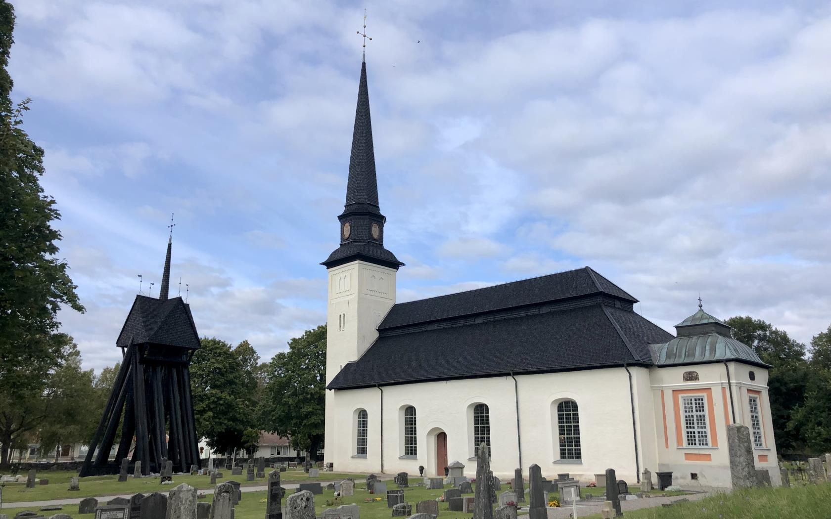 Glanshammars kyrka. Vit kyrka med svart träspånstak med gröna omgivningar