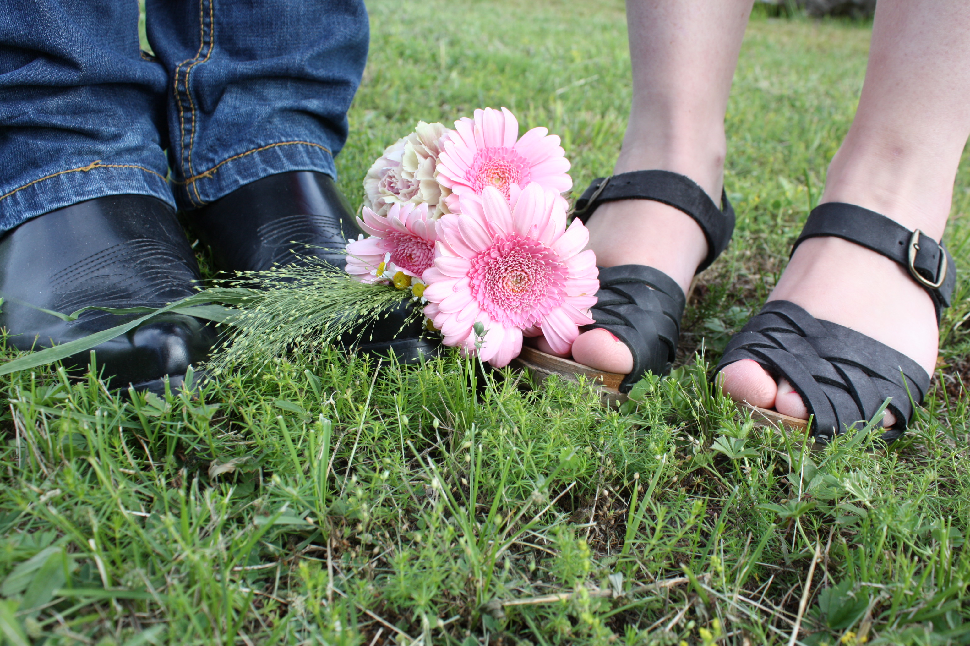 bröllopsfoto på grova skor och träskor i sandalmodell, med en rosa liten brudbukett mellan