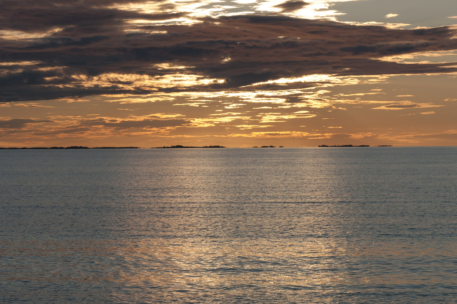 Solnedgång över havet, med gul himmel och lite moln