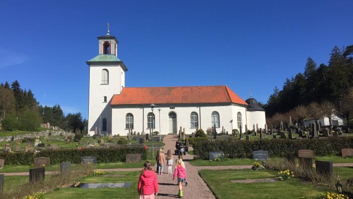 Några små barn går mot en vit kyrka