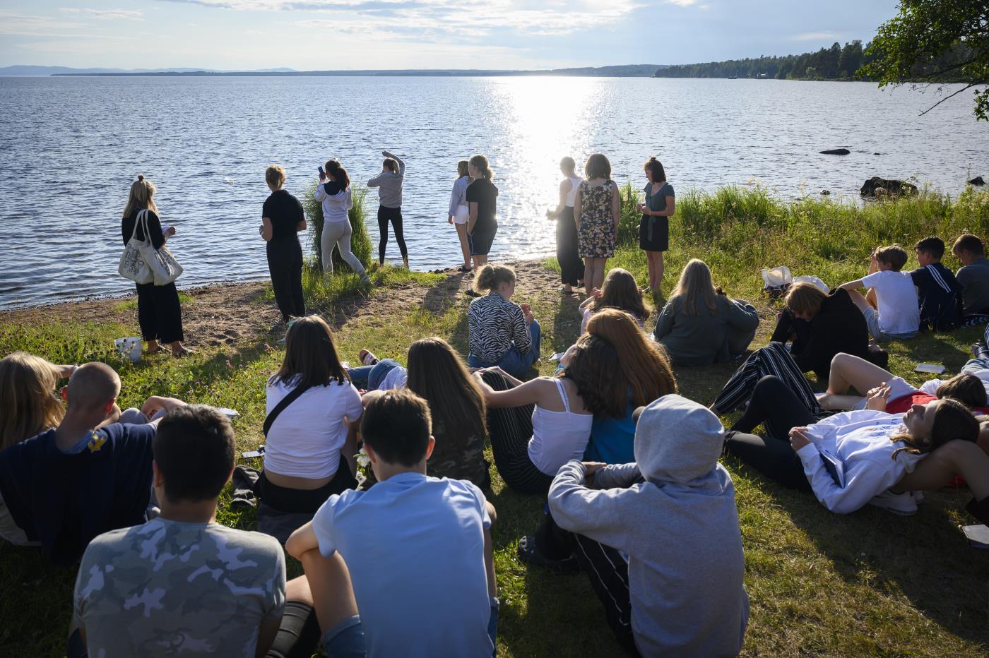 Ungdomar på en gräsmatta med havet i bakgrunden